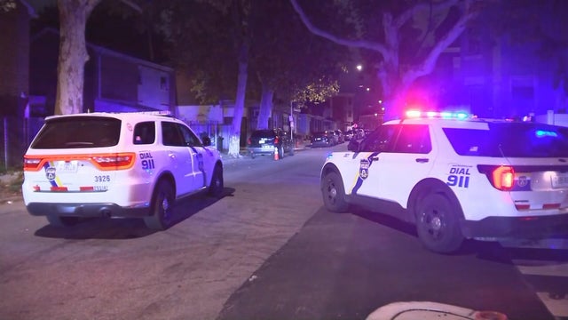 Police cars with lights on at the scene of a nighttime shooting in Philadelphia 