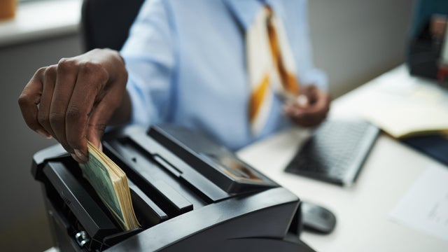 Hand of Bank Worker Counting Cash with Bill Counter in Office 