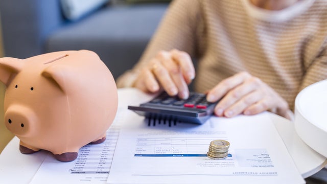 Person calculating finances with piggy bank and coins 