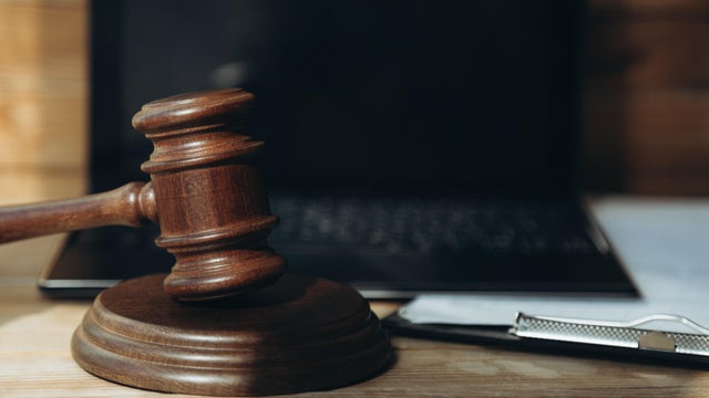 A wooden gavel and a black laptop on a desk in courtroom 