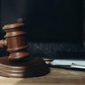A wooden gavel and a black laptop on a desk in courtroom 