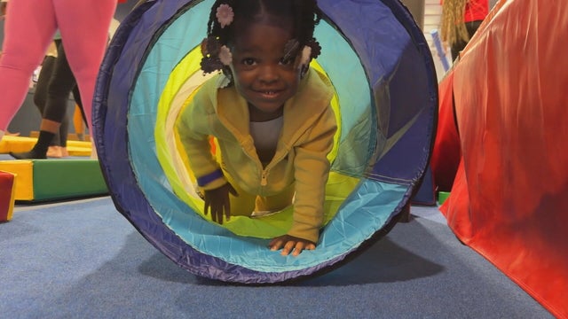 A child crawls through a big tube at a gymnastics facility 