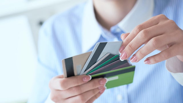 Woman hand holding various credit cards and making choice with another hand close-up. 