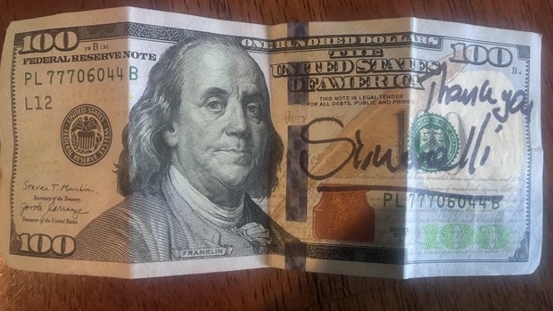 A $100 bill with "Thank you Simonelli" written on it in market