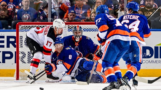 Logan Stanley #8 of the New York Islanders gets tripped up against Evan Rodrigues #17 of the New Jersey Devils as Ilya Sorokin #30 tends net during the third period at UBS Arena on October 03, 2026 in Elmont, New York. 