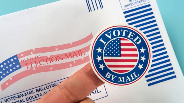 Human finger holding sticker above voting mail 