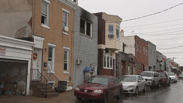 A rowhome has gray smoke damage along a residential street in Kensington 