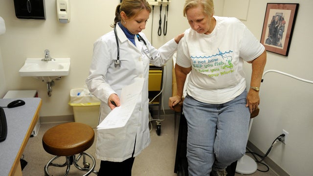 RURALHEALTH17-- Amber Buhl, left, a physician assistant at Miramont Family Medicine in Wellington, help Beverly Young, of Wellington, from the table after a follow up visit for stomach pain. Miramont Family Medicine is the only place in town to see a doct 