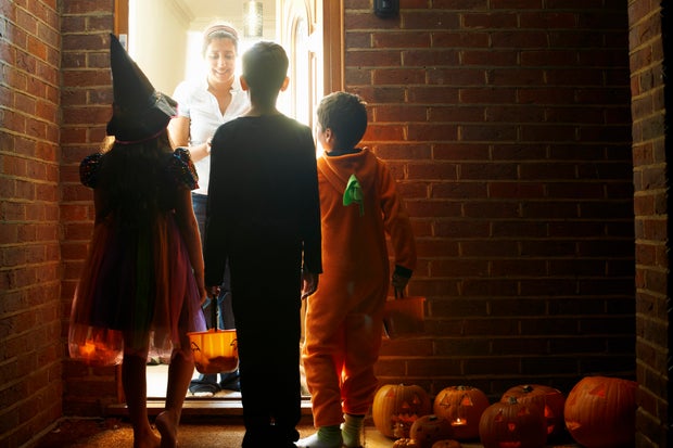 Rear view of three children wearing halloween costumes trick or treating