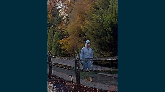 A man walks on a trail wearing a gray hooded sweatshirt 