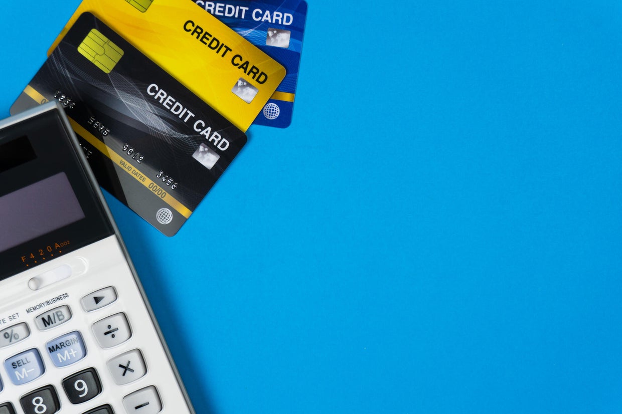 The concept of calculating debt and expenses at the end of the month. Online shopping concept. Credit card with calculator on blue background and space. Depicts expenses that need to be pay. 