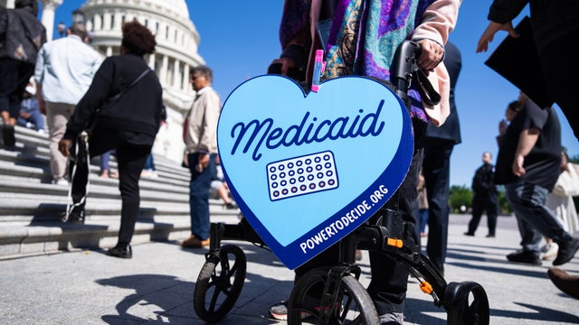 A woman carries a Medicaid sign 