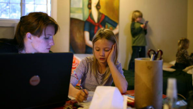 Brittney Nance helps her daughter Izabella, 7, with homework as Henry Nance, 5, and Lillie Nance, 2, play on the bed in their motel room at the Old Town Inn March 5, 2009 in West Sacramento, California. Brittney and her family were evicted from the house they were renting after her husband, Steve Nance, lost his job. The couple and their three children are living in a budget motel while they save enough money for deposit on a new rental home, but are finding it difficult as they pay nearly $1200 a month for the motel room. All five live in a small studio sized room with most of their belongings. (Photo by Justin Sullivan/Getty Images)