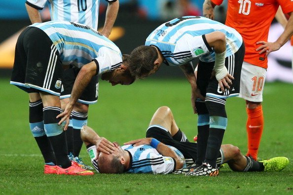 Pablo Zabaleta of Argentina lies on the pitch after a collision as teammates Rodrigo Palacio (L) and Lucas Biglia of Argentina look on during the 2014 FIFA World Cup Brazil Semi Final match between the Netherlands and Argentina (credit: Clive Rose/Getty Images)