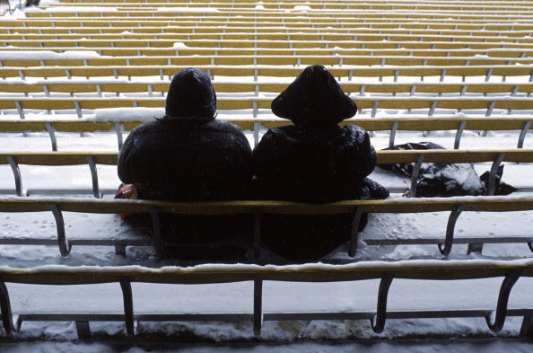 10 Dec 1989: Cold Denver Bronco fans sit in snow covered benches during a game against the New York Giants at Mile High Stadium in Denver, Colorado. The Giants defeated the Broncos 14-7.