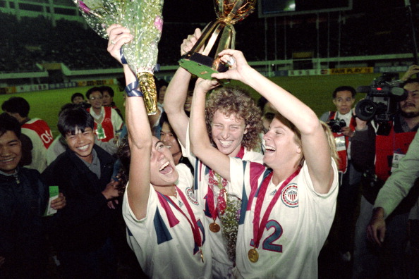 Michelle Akers-Stahl (C) who scored two goals for the US to win the first FIFA World Championship for Women's Football on November 30, 1991, holds the trophy together with teammates Julie Foudy (L) and Carin Jennings (R).